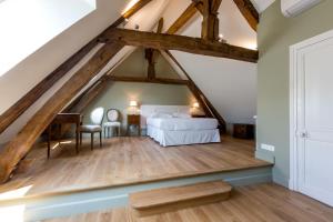 een grote slaapkamer op zolder met een bed en houten balken bij Les vignes blanches in Beaune