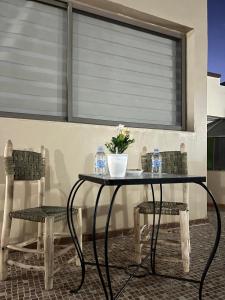 a table and two chairs with water bottles and flowers at Studio lumineux avec terrasse in Er Rachidia