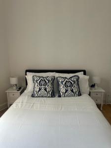 a white bed with two pillows and two tables at Cosy Double Room In The Heart of Edinburgh in Edinburgh