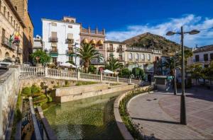 a street in a city with buildings and a river at Apartamento en centro de Cazorla con vista a la montaña in Cazorla