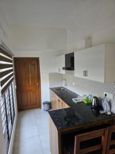 a kitchen with a black counter top and a wooden door at Atharva homes at Vallikavu Amritapuri in Perinād