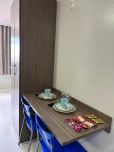 a wooden table with two cups and plates on it at flat mobiliado in Campina Grande