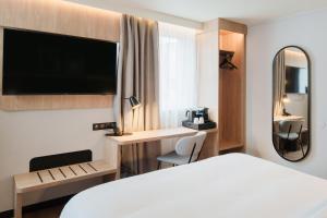 a hotel room with a white bed and a mirror at Campanile PRIME - Lyon Ouest Tassin in Tassin-la-Demi-Lune
