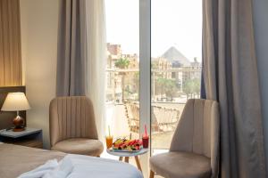 a hotel room with a bed and two chairs and a window at New dust pyramids hotel in Cairo