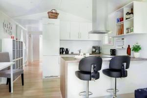 a kitchen with two black chairs and a counter at Luxurious Contemporary EkoHus 4Seasons in Tjörnarp