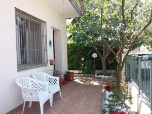 a patio with two white chairs and a tree at Casa Nicoletta Apartment in Ravenna