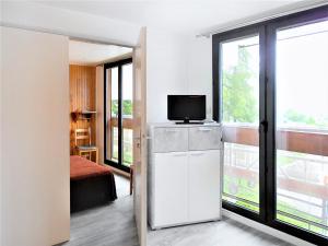 a room with a television and a room with a bed at Appartement rénové, accès direct pistes, piscine, animaux admis - FR-1-267-228 in Le Corbier