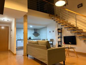 Una sala de estar con un sofá y una escalera. en Loft Almagro, en Almagro