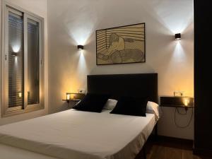 Un dormitorio con una cama con dos luces en la pared. en Loft Almagro, en Almagro