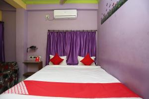a bedroom with a bed with red pillows and a purple window at Hotel O Sanjog in Bakkhali +23 photos