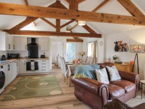 a living room with a couch and a kitchen at Oak Barn in Shrewsbury