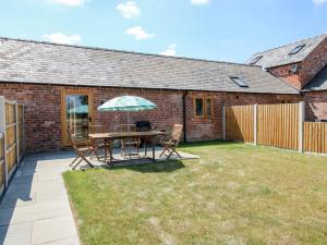 a patio with a table and chairs and an umbrella at Oak Barn in Shrewsbury
