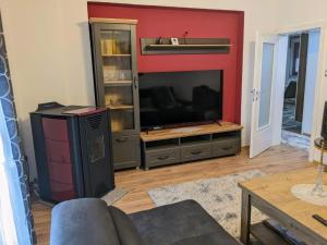 a living room with a television and a red wall at Apartmani Hrastik 1 in Bihać