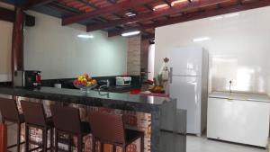a kitchen with a counter with chairs and a refrigerator at Casa de temporada em Aruanã in Aruanã
