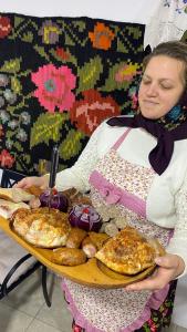 una mujer sosteniendo una bandeja de comida en una mesa en Poiana Creasta Cocoșului-Casa Floarea Soarelui, en Breb