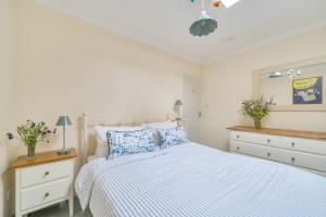 a white bedroom with a bed with blue and white sheets at Easter, Folly Lane, Salcombe in Salcombe