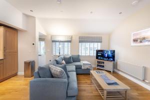 un soggiorno con un divano blu e una TV di Yew Tree Cottage a Bowland Bridge