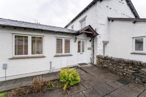 una casa bianca con un muro di pietra di Yew Tree Cottage a Bowland Bridge