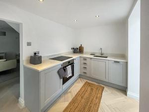 una cucina con armadi bianchi, lavandino e tappeto di Samphire Cottage a Cromer