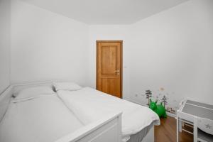 a white bedroom with a bed and a wooden door at Wunderschöner Neubau Bungalow Mit Privatem Pool Und Jacuzzi in Vozilići +14 photos