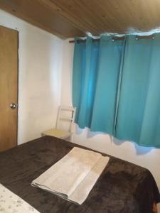 a bed in a room with blue curtains at Monoambiente Tradicional in Paysandú +4 photos