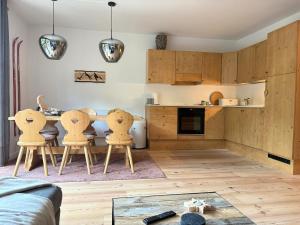 a kitchen with wooden cabinets and chairs and a table at Alpen family apartment Bergfreunde near skilift and golf course in Bad Kleinkirchheim
