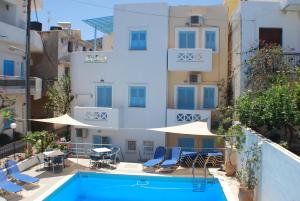 アギア・ペラギアにあるRenia Studiosの建物の隣にスイミングプール(椅子、パラソル付)