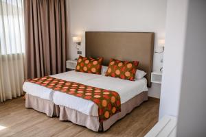 Una habitación de hotel con una cama grande con almohadas naranjas. en IG Nachosol Premium Apartments by Servatur (Adults Only), en Puerto Rico de Gran Canaria 17 fotos más