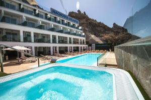 a hotel with a swimming pool and mountains in the background at IG Nachosol Atlantic & Yaizasol by Servatur - Adults Only in Puerto Rico de Gran Canaria