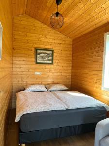 a bedroom with a bed in a wooden wall at Stormur Cottages in Vallanes