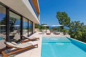 a swimming pool with lounge chairs next to a house at Opatija Luxury Villa Ella in Mošćenička Draga