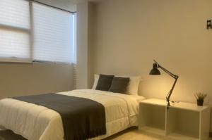 ein Schlafzimmer mit einem Bett mit einer Lampe und einem Fenster in der Unterkunft Habitación Shefa 2 in Puebla