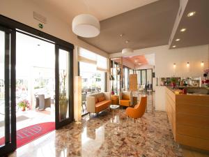 eine Lobby mit orangefarbenen Stühlen und ein Wohnzimmer in der Unterkunft Hotel Pillon in Bibione