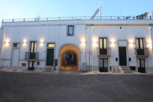a large white building with an archway and a door at Casa vacanze La Mescia in Poggiardo