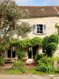 ein Haus, an dessen Seite Efeu wächst in der Unterkunft Ferme des Millonets - petit gîte in Vienne-en-Arthies