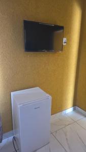 un réfrigérateur blanc et une télévision sur un mur dans l'établissement Neethling 6 Guest House, à Johannesbourg