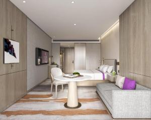 a bedroom with a bed and a table and a couch at Elong Hotel Jakarta PIK in Jakarta