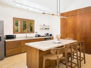 a kitchen with wooden cabinets and a island with bar stools at Tropical Roga Villa with Private Pool in Cabarete +23 photos