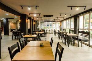 a restaurant with wooden tables and chairs and windows at Ibis Joao Pessoa Praia in João Pessoa