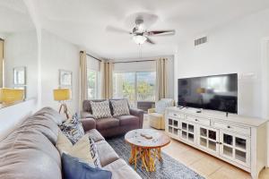 een woonkamer met een bank en een flatscreen-tv bij Sunset Vistas Condo 203S in St Pete Beach