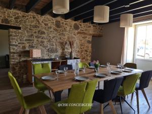 ein Esszimmer mit einem Holztisch und grünen Stühlen in der Unterkunft Maison de campagne HDH - Charme et moderne - Proche du Puy duFou in LʼÉpaux