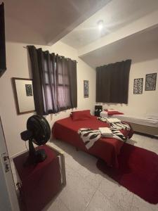 a bedroom with a bed with a red comforter at Pousada São Marcos in Santos