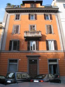 un edificio anaranjado con balcón y coches aparcados frente a él en Rome Studio Rental, en Roma