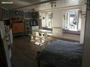 a living room with a table and a kitchen at Gîtes du Café de la poste in Le Buisson