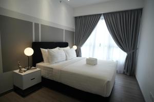 a bedroom with a large white bed with a window at Luxury Suites at Wyndham KLCC in Kuala Lumpur