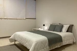 a white bedroom with a large bed and a window at Habitación Shefa Solar 3 in Puebla