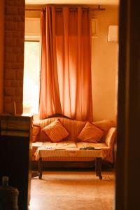 a couch in front of a window with an orange curtain at Room in central Amman in Amman