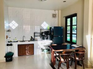 a kitchen with a table and a refrigerator at BAAN JUBJUB Chaloklum in Chaloklum