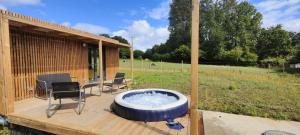 a hot tub sitting on a deck with two chairs at La Cabane du Gouët in Saint-Julien
