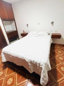 Un dormitorio con una cama blanca con dos mesitas de noche. en departamento acogedor en la Molina, en Lima